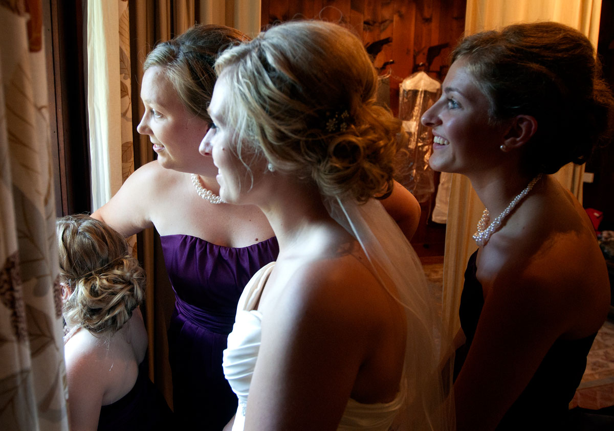 Kari watches from the bridle room with her sisters, Miah and Lauren, and Beth as seats fill up for the outdoor wedding at Mayowood Stone Barn