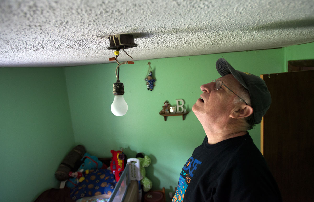Jim Stocks inspects the wiring of a ceiling light in a bedroom at a home in eastern Kentucky. The light could only be turned on when the home's kitchen light was also on.