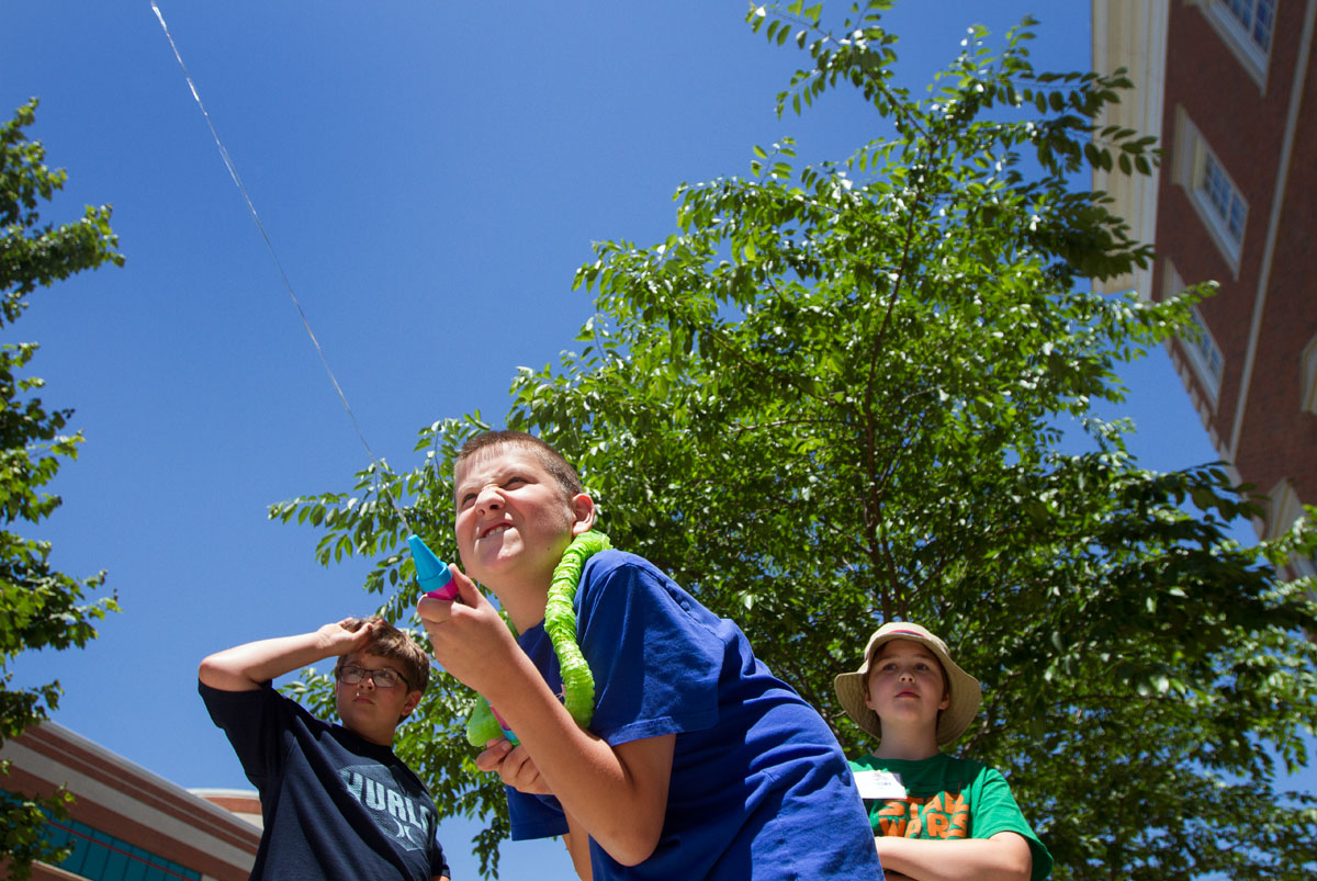 Destry Miller squirts a water launcher as his group members Christian Kantosky (left) and Anthony Counts watch during Math at Camp Innovate Monday, June 6. The students used various water tools and took measurements to find which sent water the furthest.